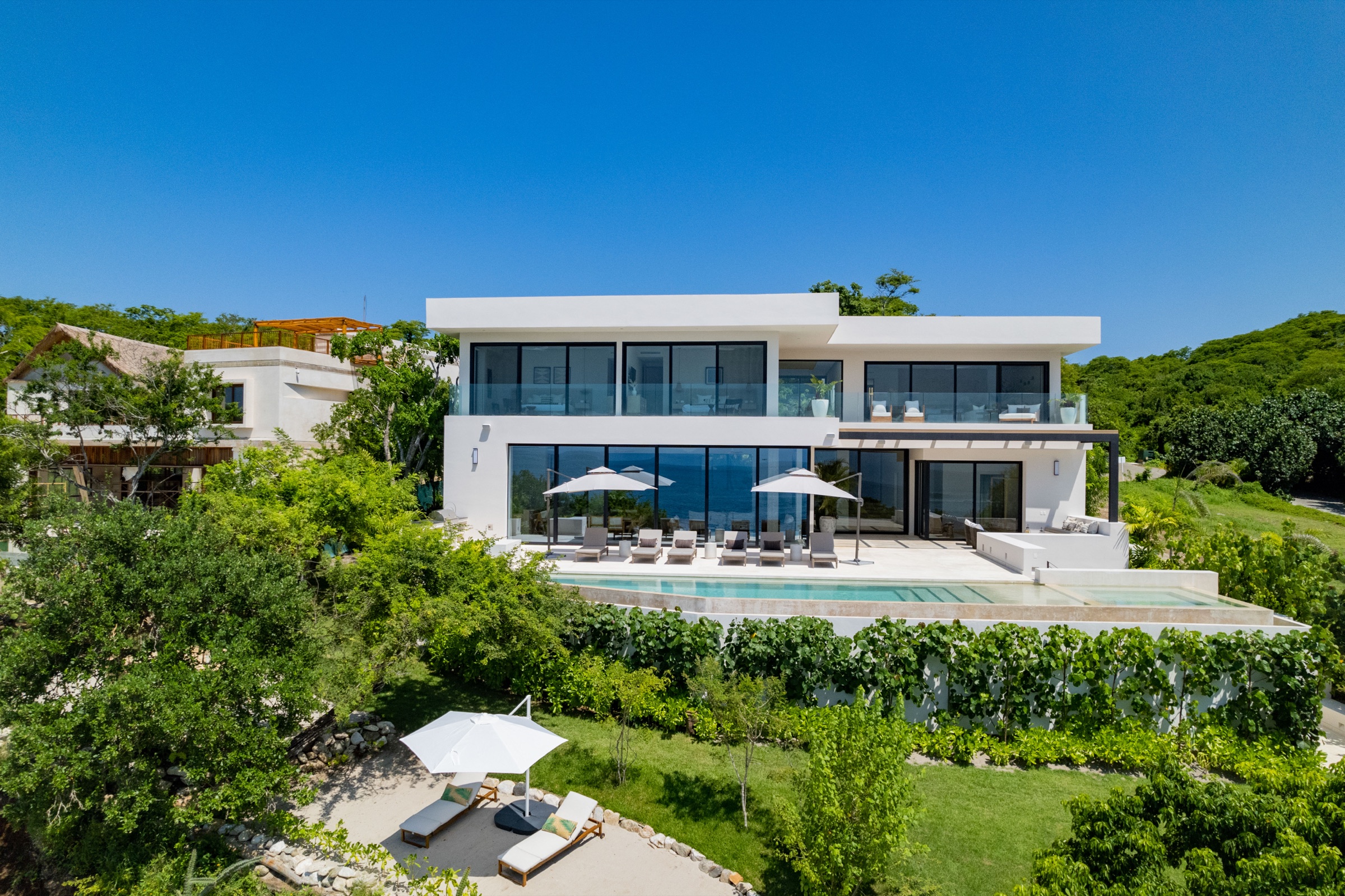 Casa Todos Juntos in daylight with its pool, garden, and oceanfront terrace